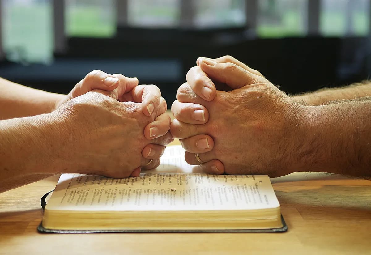 Folded hands over Bible