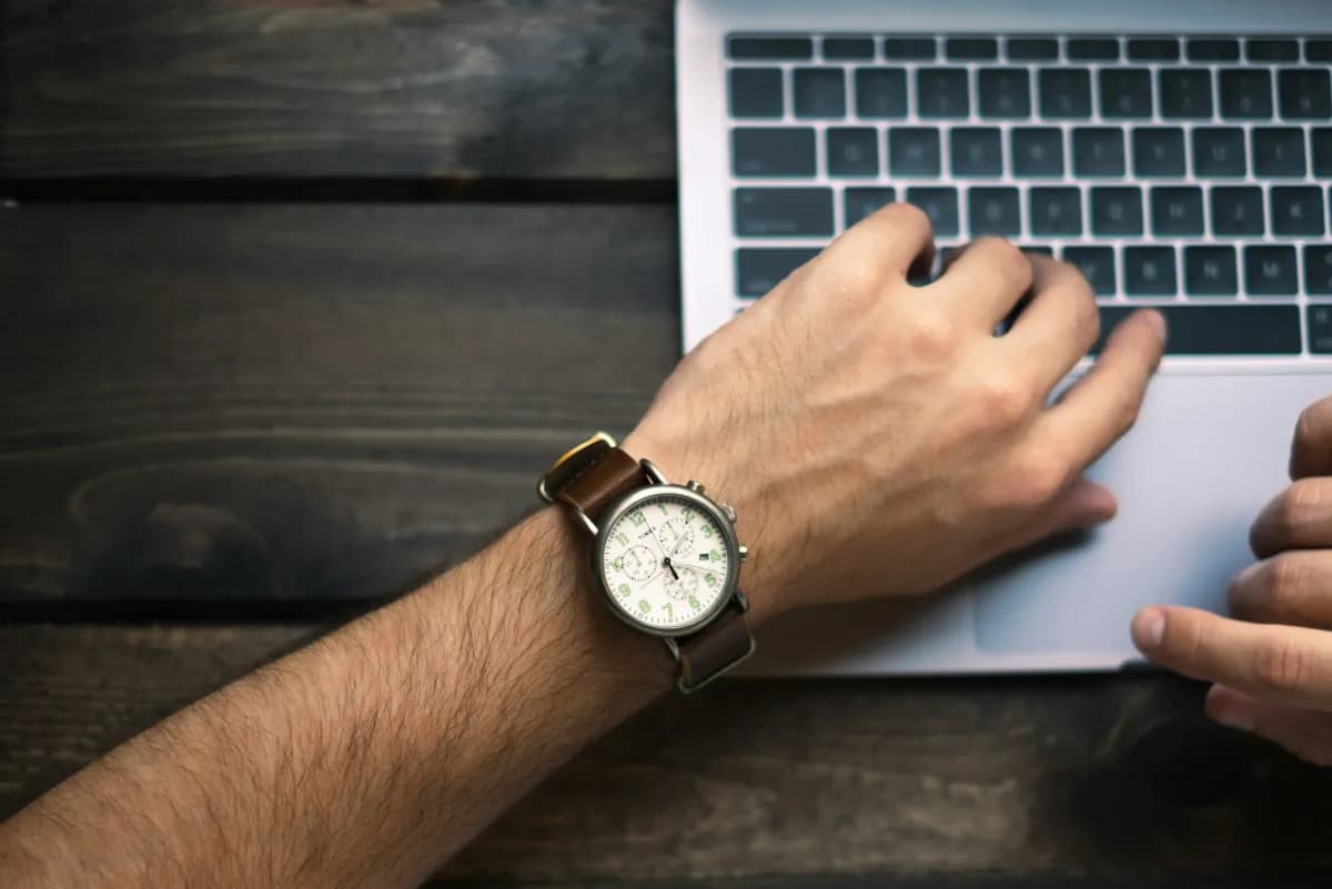 Hand wearing watch on laptop keyboard